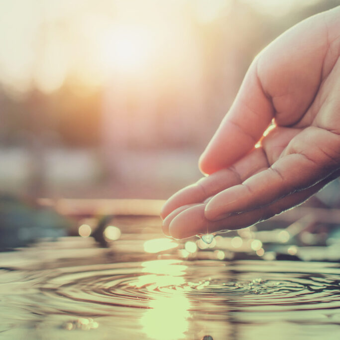 hand and water with sunset